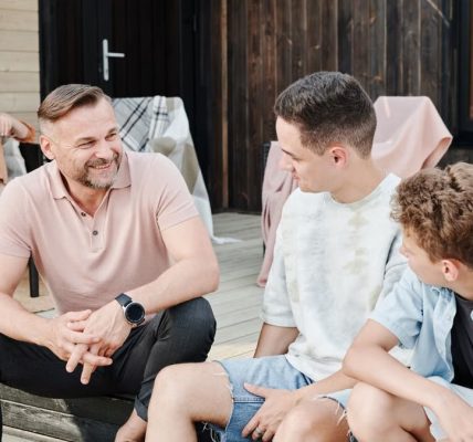 Family sharing quality time on a wooden terrace. Smiling and conversing.