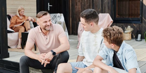 Family sharing quality time on a wooden terrace. Smiling and conversing.