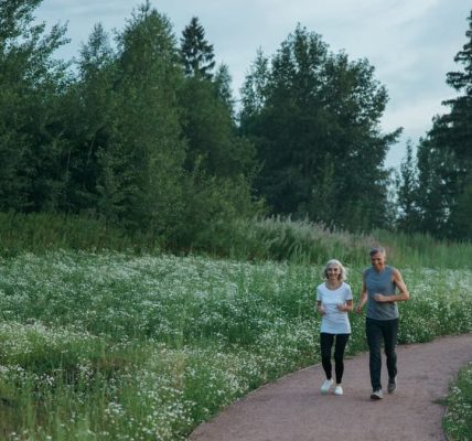 Senior couple jogging on a scenic park path surrounded by greenery.